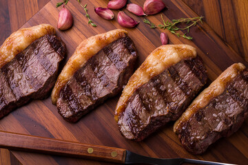 Grilled Beef Picanha Steaks on Cutting Board with Garlic and Herbs