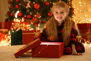 Cute little girl opening Christmas gift at home