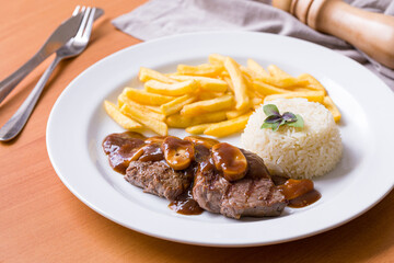 Delicious Steak with Mushroom Sauce, Fries and Rice