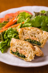 Delicious Salmon and Spinach Pastry with Fresh Salad on Plate