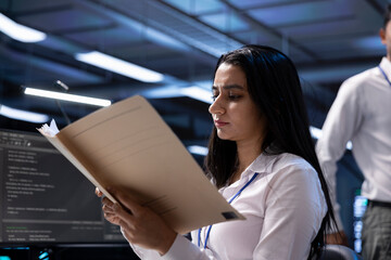 Data center supervisor checking emergency procedures paperwork to ensure company continuity in case...