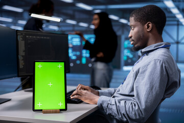 Supervisor using chroma key tablet to reconfigure server room, optimizing it for data processing requirements. Manager using isolated screen device, ensuring data center tech operates efficiently
