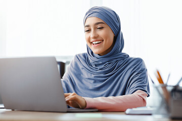 Business Correspondence. Portrait Of Smiling Arabic Female Entrepreneur In Hijab Using Laptop At...