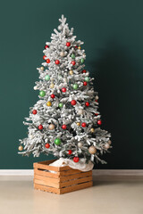 Fir tree decorated with beautiful Christmas balls against dark color wall