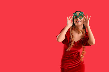 Young woman in Christmas eyeglasses on red background