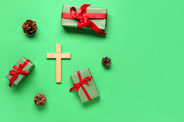 Cross with gifts and pine cones on green background. Concept of Christmas story