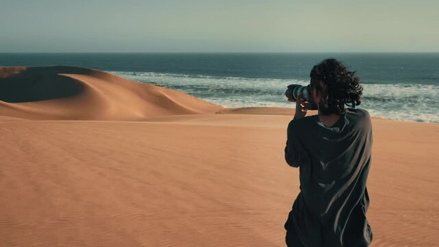 A photographer walking on the dunes of the desert in Namibia . 