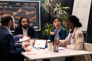Colleagues evaluating infographics data analysis in an executive meeting, corporate restructuring...