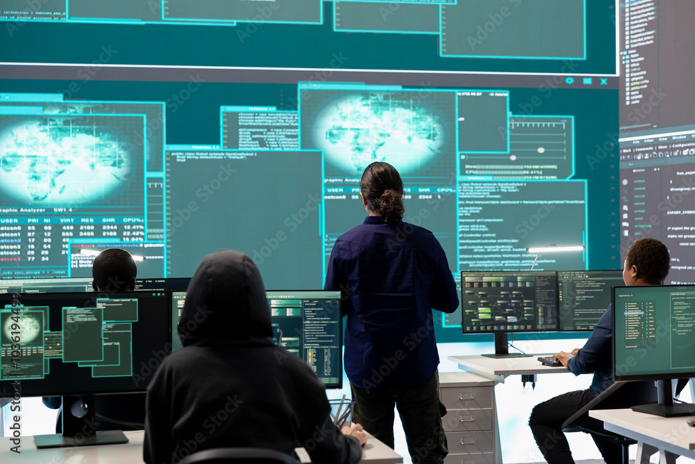 Poster governmental hacker examines info on a big screen in agency office, using advanced technology to sec