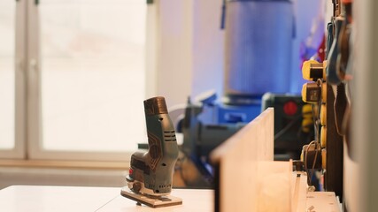 Chisels, screwdrivers, wrench and pliers on wall in furniture assembly shop next to electric router on workbench. Close up of woodworking gear on rack in joinery and power tool