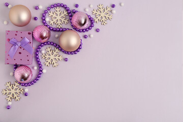 Beautiful composition with gift, Christmas balls, snowflakes and purple beads garland on light background