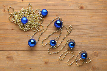 Beautiful composition with blue Christmas balls and beads garland on wooden background