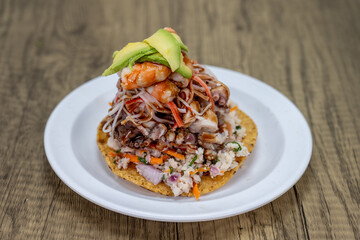 Delicious looking tostada mixta stacked high on a tortilla and topped with shrimp for an excellent Mexican seafood meal