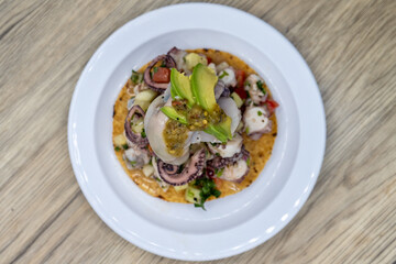 Overhead view of delicious looking tostada poca madre stacked high on a tortilla and topped with oyster and octopus for an excellent Mexcian seafood meal