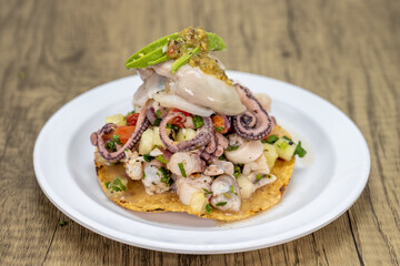 Delicious looking tostada poca madre stacked high on a tortilla and topped with oyster and octopus for an excellent Mexcian seafood meal
