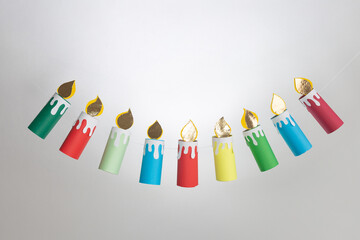 Colorful paper candle garland hanging on a light background. Step in creative process. Festive and...