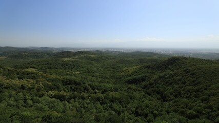Naklejka premium Lush green hills with distant cityscape under blue sky, Georgia