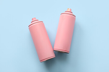 Spray paint cans on blue background