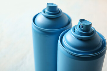 Spray paint cans on light grunge background, closeup