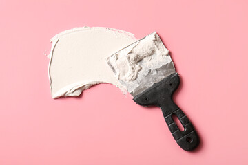 Knife with putty on pink background