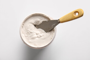 Knife and can of putty on white background