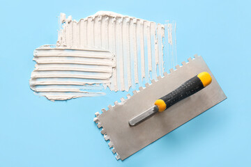 Trowel and white putty on blue background