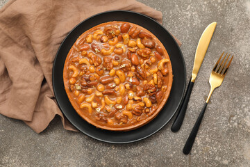 Plate of sweet tart with different nuts and caramel on grey background
