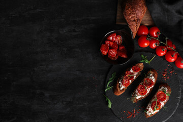 Board of tasty tomato bruschetta with ricotta on black background