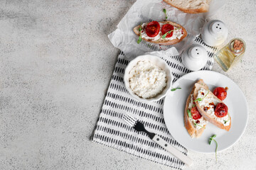 Plate and baking paper of tasty tomato bruschetta with ricotta on white background