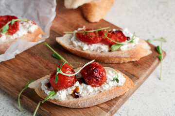 Wooden board of tasty tomato bruschetta with ricotta on white background