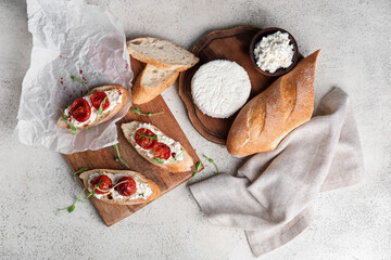 Wooden board of tasty tomato bruschetta with ricotta on white background