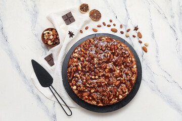 Black board of sweet tart with different nuts and ingredients on white background