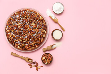 Plate of sweet tart with different nuts and ingredients on pink background