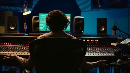 Music engineer producing sounds with mixing console and daw software interface, working on a new...
