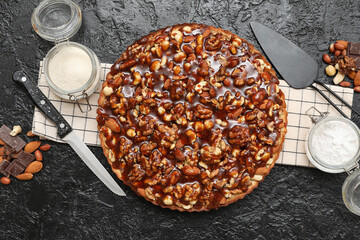 Sweet tart with different nuts and ingredients on black background