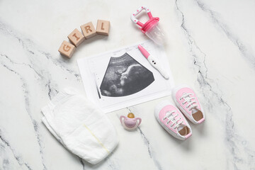 Composition with baby shoes, sonogram image, pregnancy test and word GIRL on grunge white background