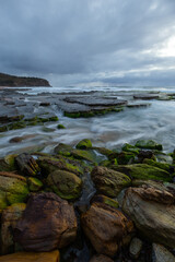 Wave water flowing around the rocks on the shore.