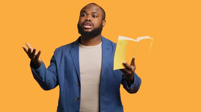 Man reading book aloud, narrating story for audience, doing monologue for theatre play. Person rehearsing using literature novel source material, reciting from pages, studio background, camera A