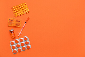 Pill box, blister pack with pills, syringe and ampule on orange background