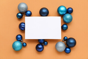 Blank card and Christmas balls on orange background