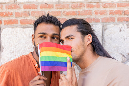 Gay couple embracing with pride flag in urban setting