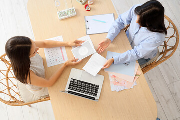 Female wedding planner with client choosing invitations at table in office, top view