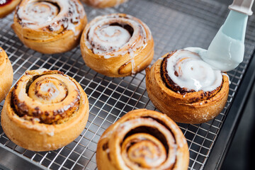 Freshly baked cinnamon rolls being glazed