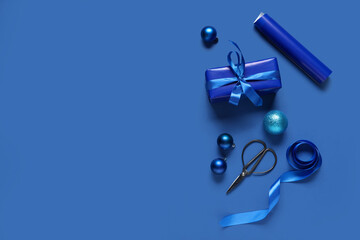 Christmas gift box with packing materials and different decorations on blue background