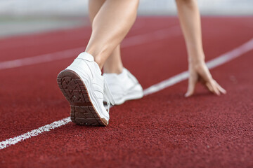 Legs of young woman in crouch start position at stadium, closeup