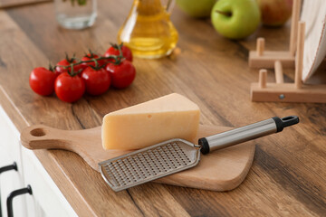 Cutting board with grater and cheese on table in kitchen