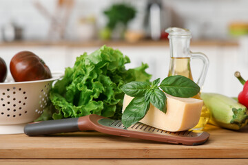 Grater and ingredients on wooden cutting board in kitchen, closeup