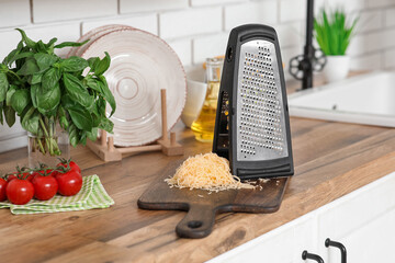 Grater, ingredients and cutting board on wooden table in kitchen