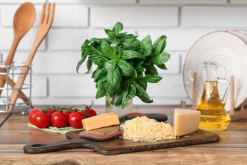Grater, cheese and cutting board on wooden table in kitchen