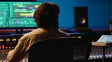 Audio technician working in control room to edit and process tracks, using audio software on pc for...
